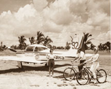 Rockwell Standard Corp. Commander 200 airplane parked at the air terminal and bicycle riders